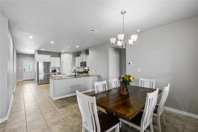 dining space with light tile patterned flooring, sink, and an inviting chandelier