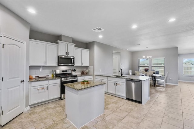 kitchen with white cabinets, sink, light stone countertops, and stainless steel appliances