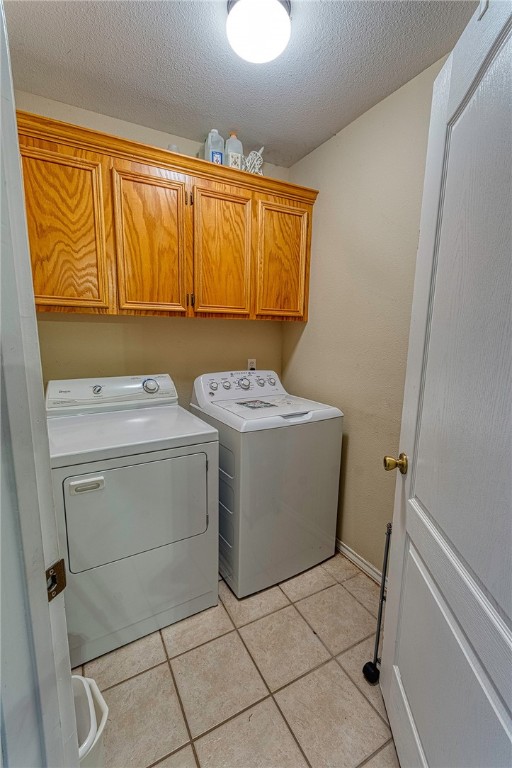 7014 Mona Lisa Cir, Corpus Christi, TX 78413 - laundry area with cabinet space, washing machine and dryer, a textured ceiling, and light tile patterned flooring