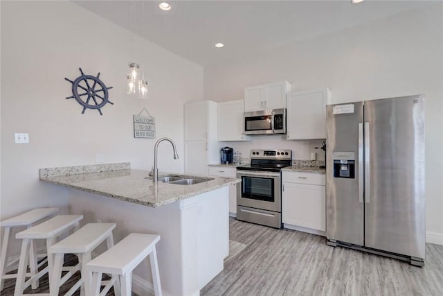 kitchen featuring a kitchen bar, sink, kitchen peninsula, stainless steel appliances, and white cabinets