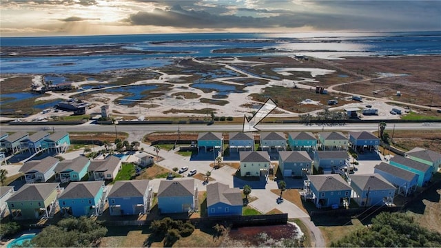 aerial view at dusk featuring a view of the beach and a water view