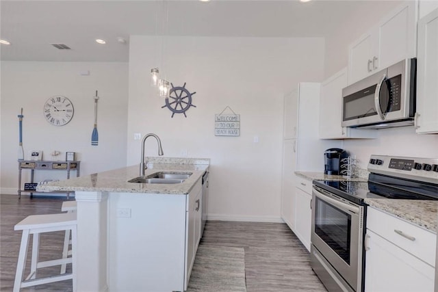 kitchen with white cabinetry, sink, a kitchen bar, light stone counters, and stainless steel appliances