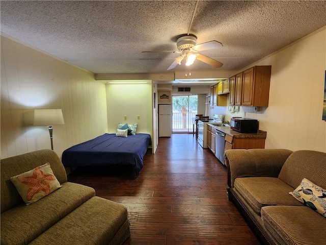 bedroom with ceiling fan, white refrigerator, a textured ceiling, and dark wood-type flooring