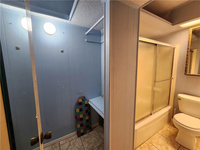 bathroom featuring a textured ceiling, tile patterned flooring, combined bath / shower with glass door, and toilet