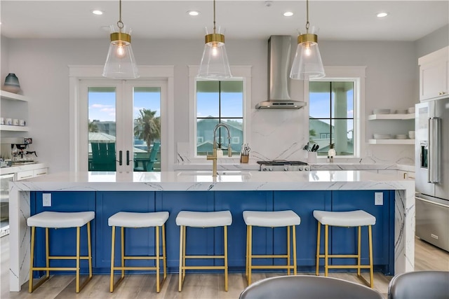 969 Banyan Beach Dr, Port Aransas, TX 78373 - kitchen featuring high end refrigerator, wall chimney range hood, a sink, recessed lighting, and light stone countertops