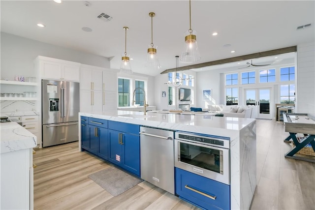 969 Banyan Beach Dr, Port Aransas, TX 78373 - kitchen with appliances with stainless steel finishes, blue cabinets, a sink, light wood-style floors, and white cabinets