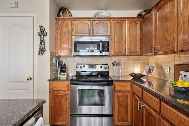 kitchen featuring brown cabinetry, appliances with stainless steel finishes, decorative backsplash, and dark stone counters