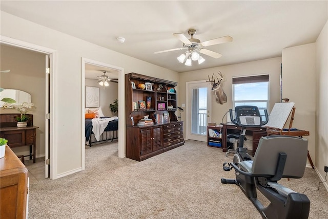 carpeted office space with a ceiling fan and baseboards