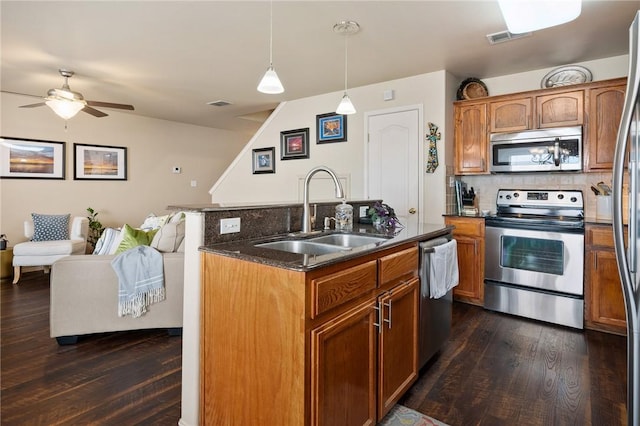 kitchen with dark wood finished floors, stainless steel appliances, tasteful backsplash, visible vents, and a sink