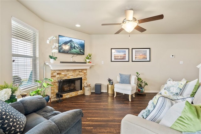 living area with recessed lighting, ceiling fan, a stone fireplace, wood finished floors, and baseboards