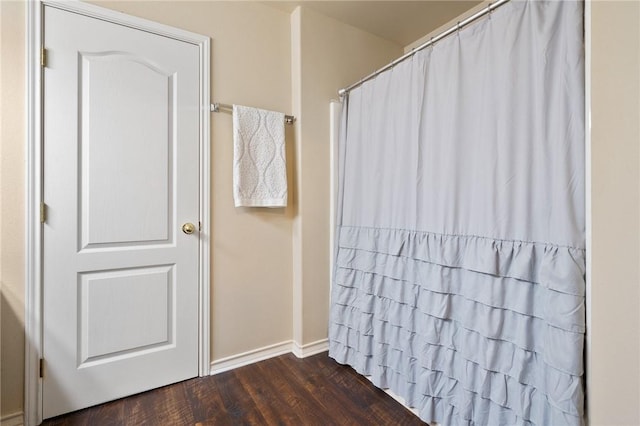 bathroom featuring a shower with curtain, baseboards, and wood finished floors