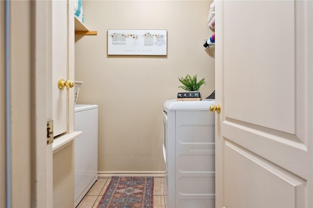 clothes washing area with laundry area, light tile patterned flooring, baseboards, and separate washer and dryer