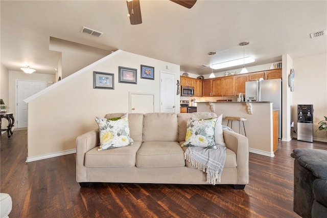 living room with dark wood finished floors, visible vents, and baseboards