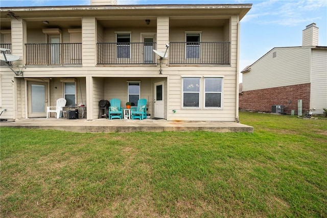 rear view of house featuring central air condition unit, a patio area, a balcony, and a lawn