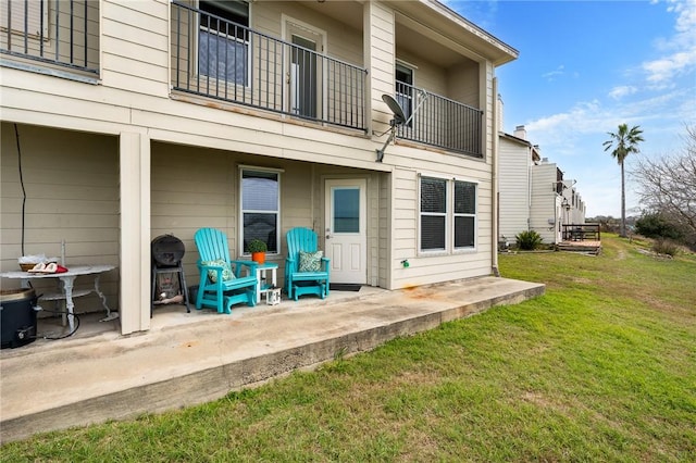 rear view of property featuring a lawn and a balcony