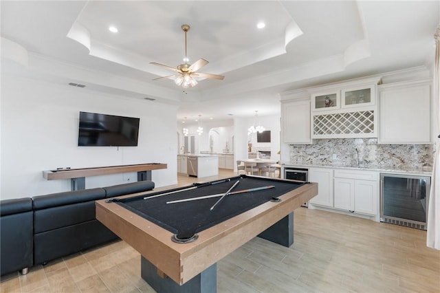 game room with wet bar, wine cooler, billiards, a tray ceiling, and ceiling fan with notable chandelier