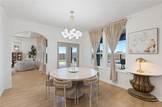 dining space with french doors, an inviting chandelier, ornamental molding, and light hardwood / wood-style flooring