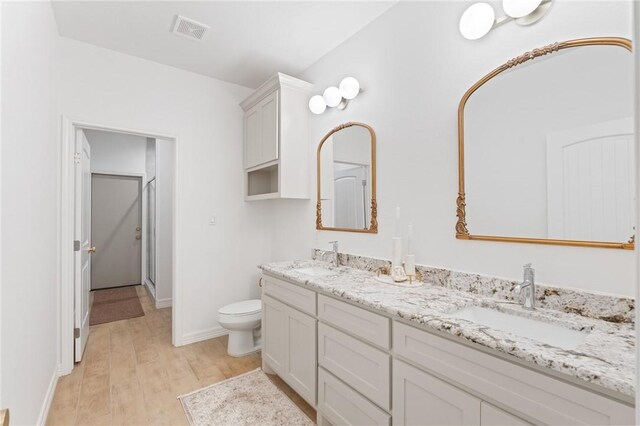 bathroom with a shower with door, vanity, wood-type flooring, and toilet