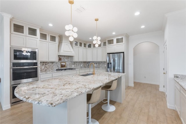 kitchen with white cabinets, stainless steel appliances, and a kitchen island with sink