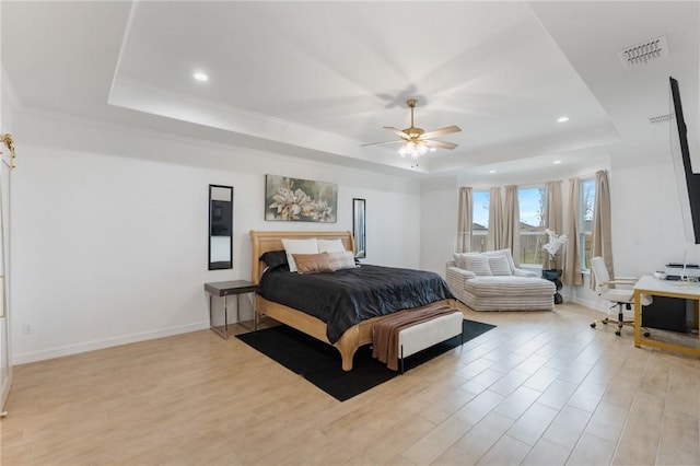 bedroom with a tray ceiling, ceiling fan, and light hardwood / wood-style flooring