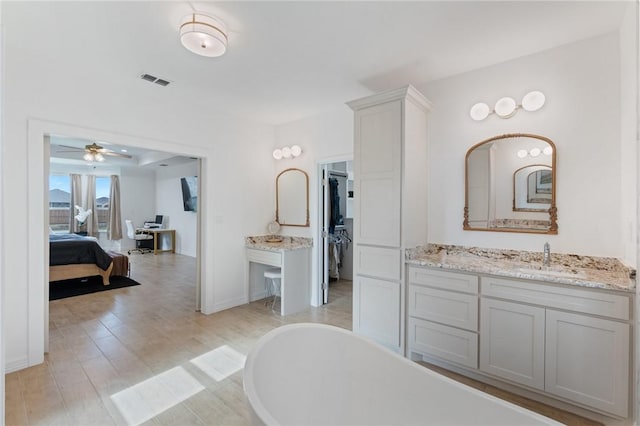 bathroom with ceiling fan, wood-type flooring, a tub, and vanity