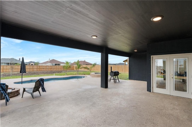 view of patio / terrace with a swimming pool with hot tub, french doors, and a fire pit