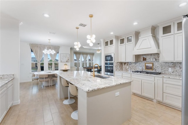 kitchen featuring white cabinetry, custom range hood, stainless steel appliances, and a chandelier