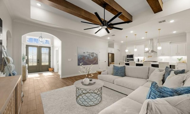 living room featuring beam ceiling, crown molding, french doors, and ceiling fan with notable chandelier