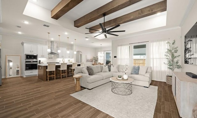 living room featuring beamed ceiling, ceiling fan, and ornamental molding