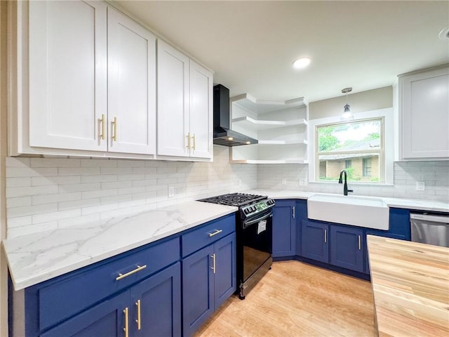 kitchen featuring sink, white cabinets, wall chimney exhaust hood, black gas range oven, and pendant lighting