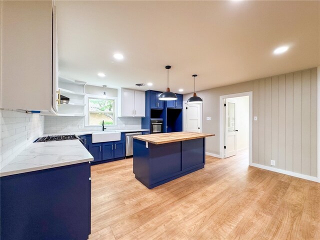 kitchen with stainless steel appliances, blue cabinets, sink, a center island, and tasteful backsplash