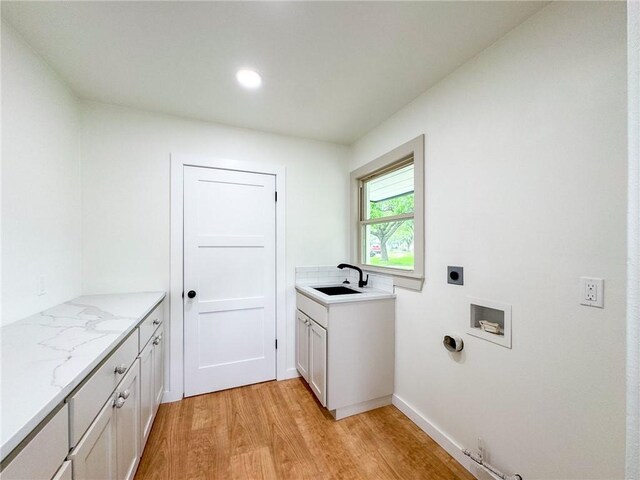 clothes washing area featuring cabinets, light wood-type flooring, hookup for a washing machine, electric dryer hookup, and sink