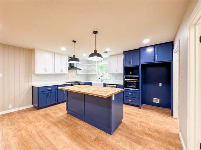 kitchen with butcher block counters, blue cabinets, white cabinets, and a center island