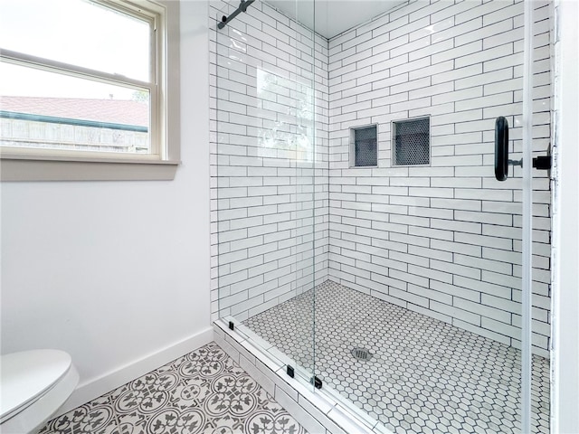 bathroom featuring toilet, an enclosed shower, and tile patterned floors