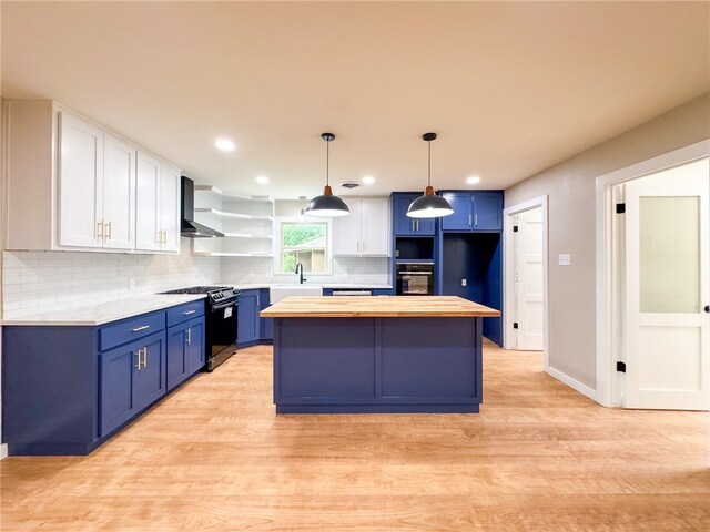 kitchen with wall chimney exhaust hood, a center island, black appliances, butcher block countertops, and white cabinets