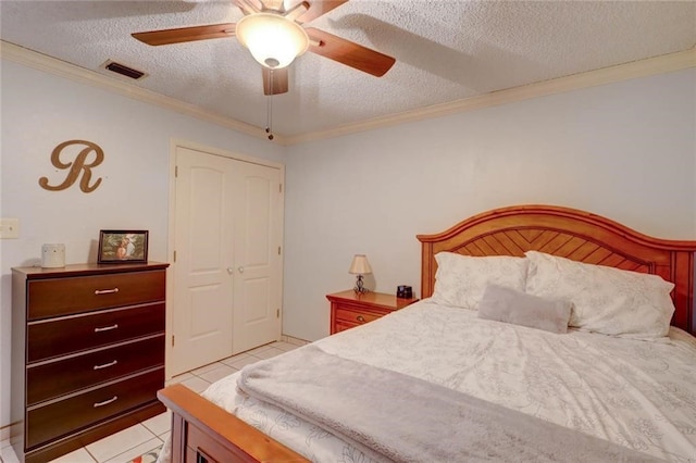 tiled bedroom with ceiling fan, a textured ceiling, a closet, and crown molding