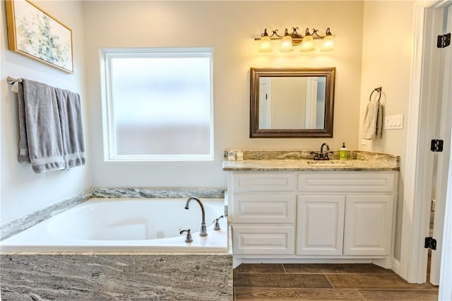 bathroom featuring a relaxing tiled tub and vanity