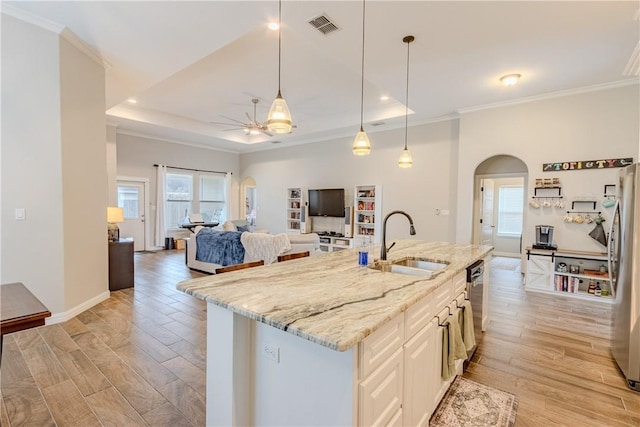 kitchen featuring pendant lighting, sink, a kitchen island with sink, light stone countertops, and light wood-type flooring