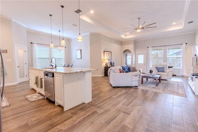 kitchen featuring a center island with sink, a raised ceiling, hanging light fixtures, and stainless steel dishwasher