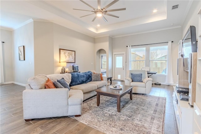 living room featuring ornamental molding, ceiling fan, light hardwood / wood-style floors, and a tray ceiling