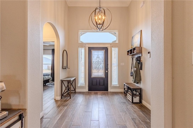 entrance foyer featuring an inviting chandelier, a towering ceiling, ornamental molding, and hardwood / wood-style floors