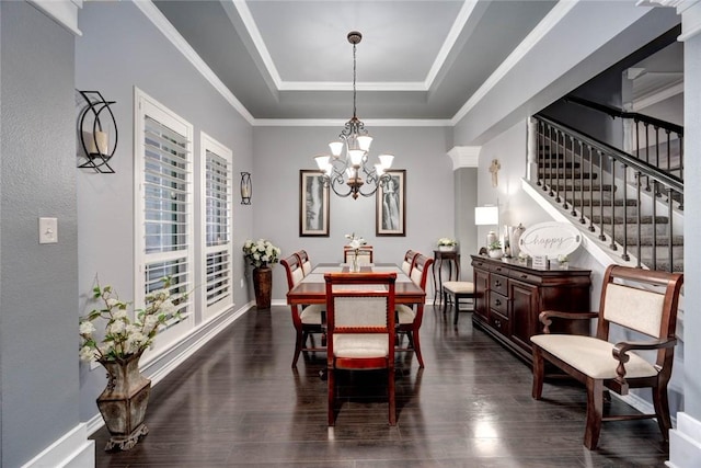 dining space with a tray ceiling, a notable chandelier, dark wood finished floors, baseboards, and stairs