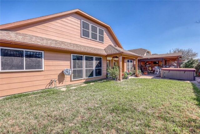 back of property featuring a patio area, a lawn, a hot tub, and roof with shingles