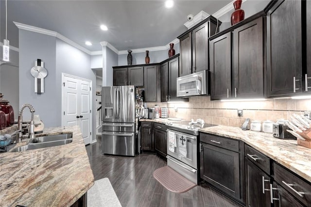 kitchen featuring stainless steel appliances, dark wood-style flooring, a sink, decorative backsplash, and light stone countertops