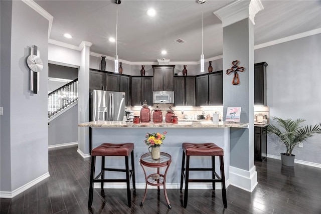 kitchen with white microwave, a breakfast bar area, stainless steel fridge, and visible vents