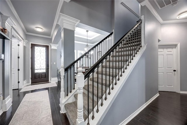 foyer with crown molding, dark wood-style flooring, decorative columns, and baseboards