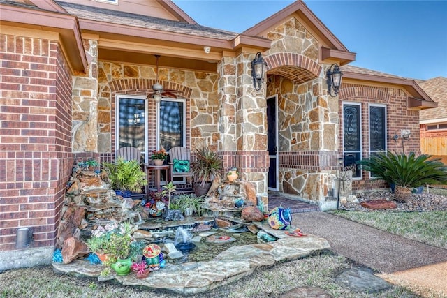 view of exterior entry featuring stone siding, brick siding, and roof with shingles