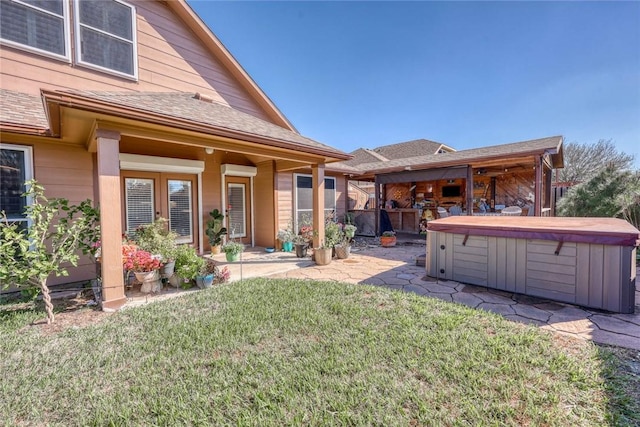 back of house with a patio, a shingled roof, a lawn, and a hot tub