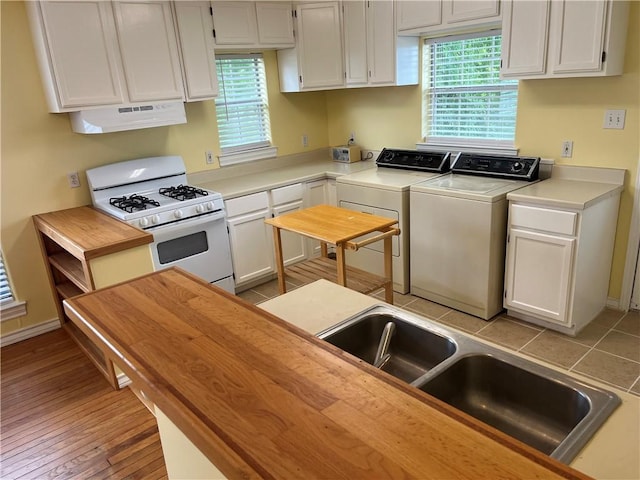 822 Indiana Ave, Corpus Christi, TX 78404 - kitchen with washer and dryer, under cabinet range hood, white cabinetry, and gas range gas stove