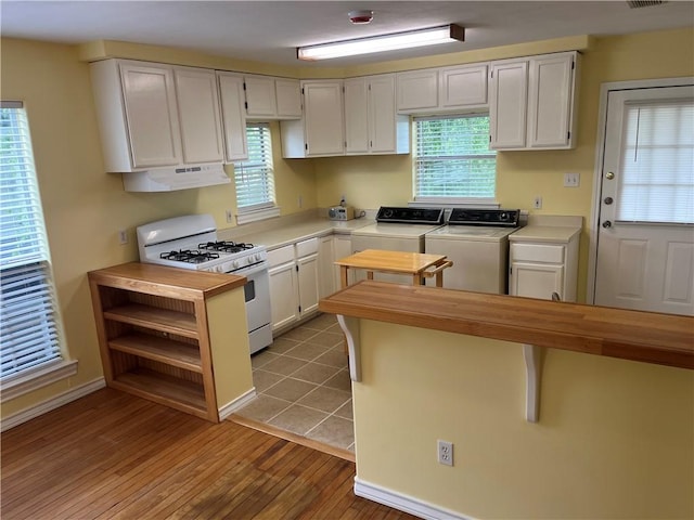822 Indiana Ave, Corpus Christi, TX 78404 - kitchen featuring light wood-style flooring, white cabinetry, white range with gas stovetop, independent washer and dryer, and under cabinet range hood